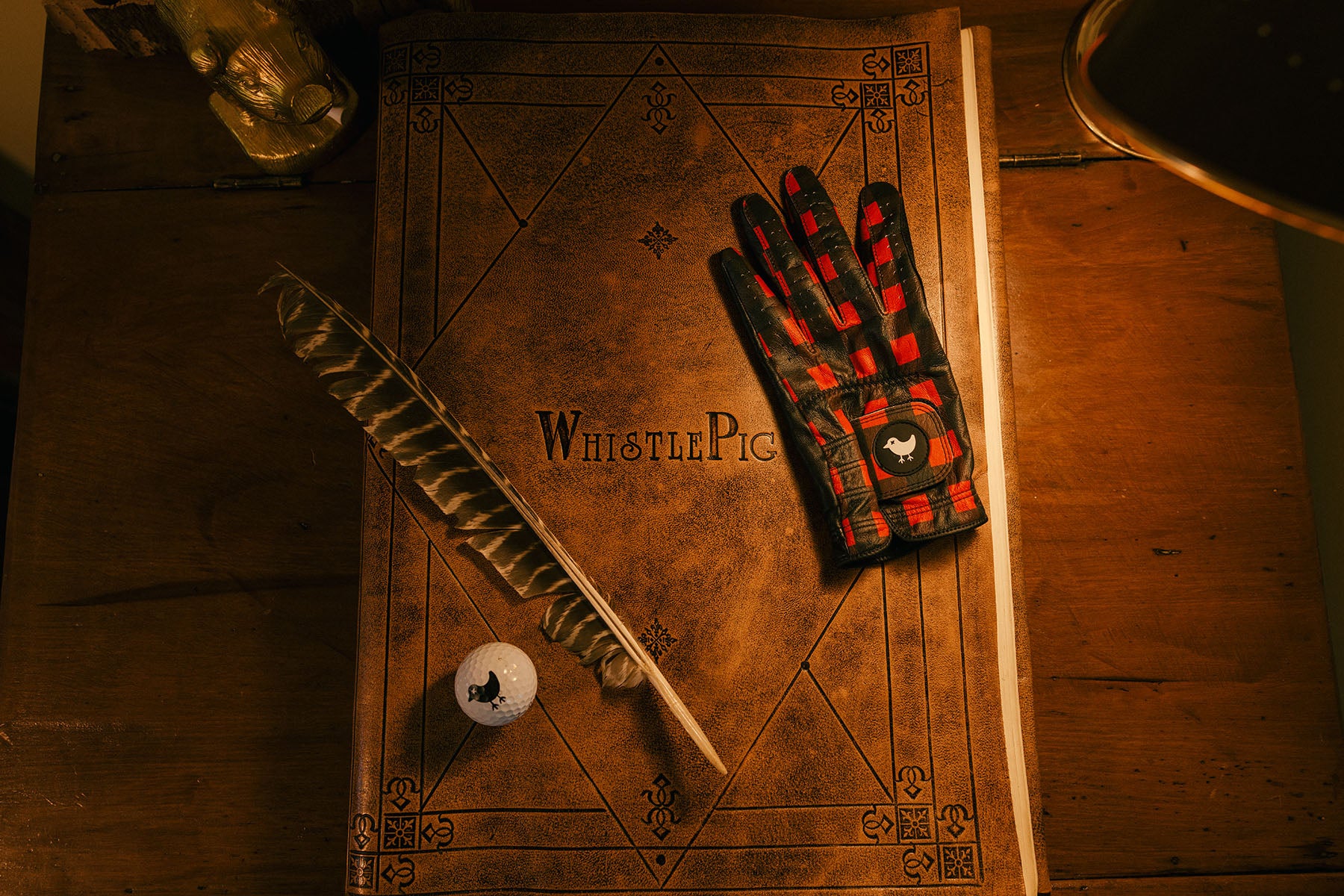 Gloves and a feather pen on an old book with 'Whistle Pig' branding.