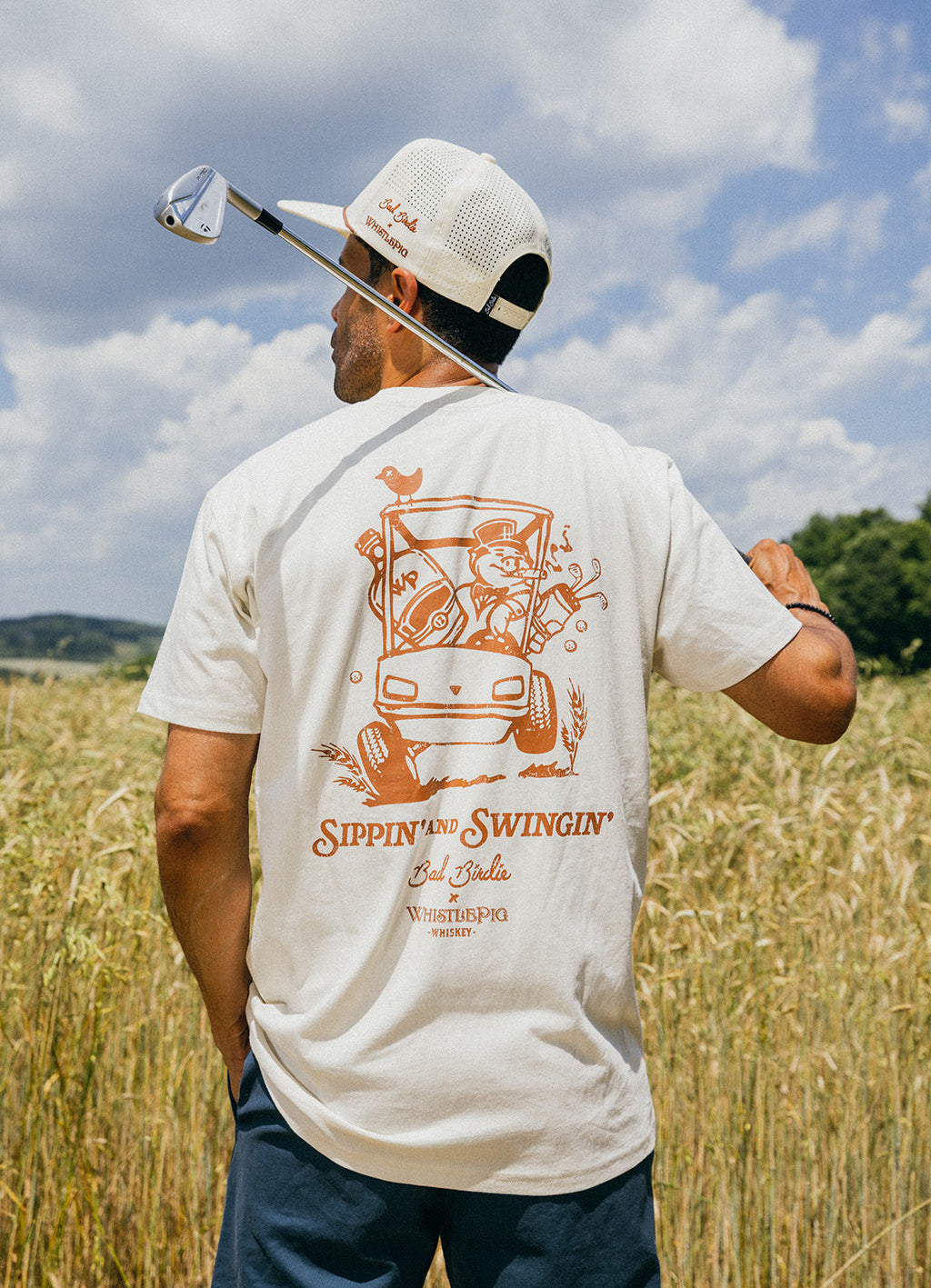 Man in a field wearing a t-shirt with a graphic design and text.