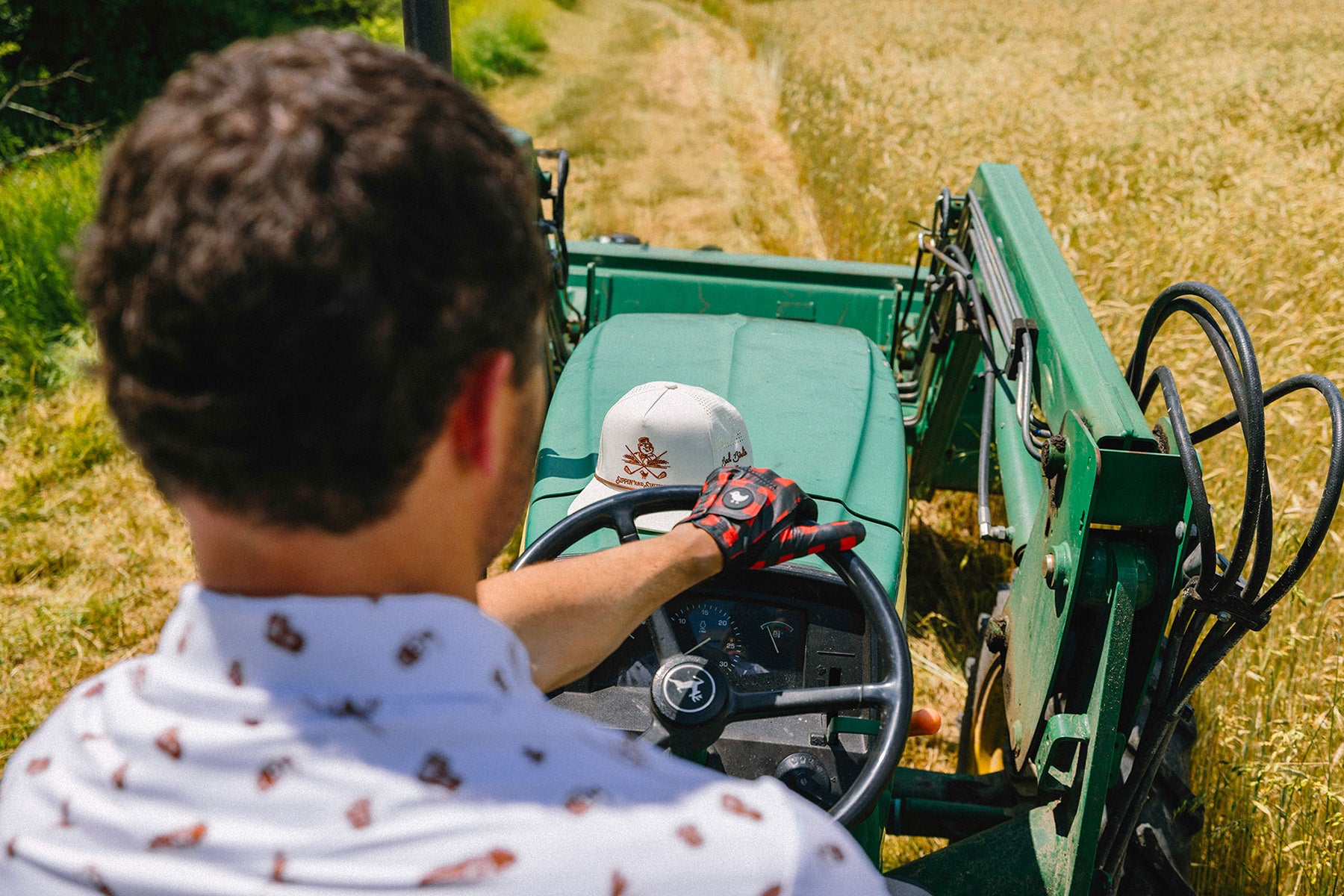 Two people operating a green agricultural machine in a field.